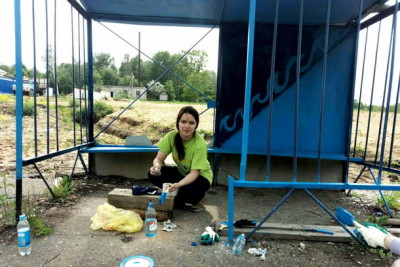 Валентина Егорова «набирает опыт» на покраске остановки. Фото: Анастасия КРОТОВА